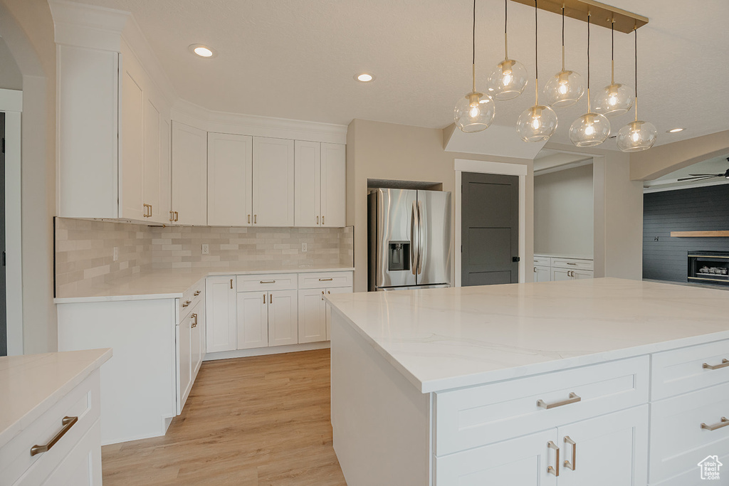 Kitchen with stainless steel fridge with ice dispenser, decorative backsplash, light wood-style floors, white cabinetry, and recessed lighting