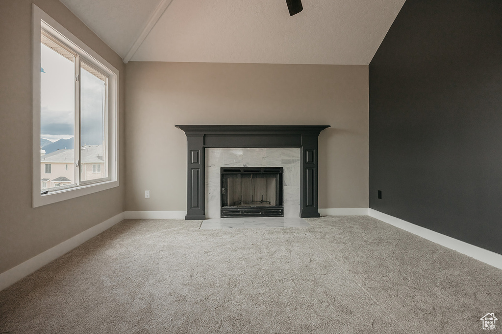 Unfurnished living room featuring vaulted ceiling, carpet floors, a premium fireplace, and baseboards