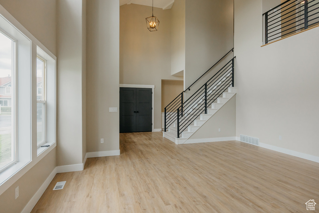 Foyer entrance featuring a high ceiling, healthy amount of natural light, wood finished floors, stairway, and baseboards