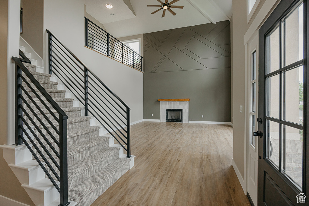 Foyer entrance featuring stairway, baseboards, wood finished floors, a tile fireplace, and a ceiling fan