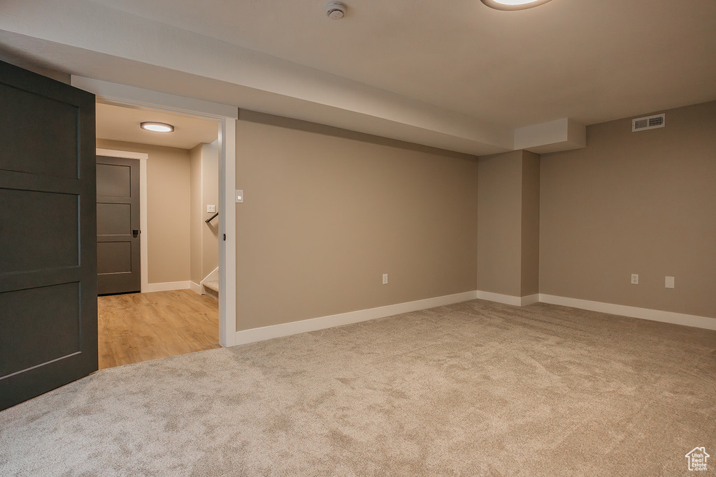 Finished basement featuring light colored carpet, baseboards, and stairway