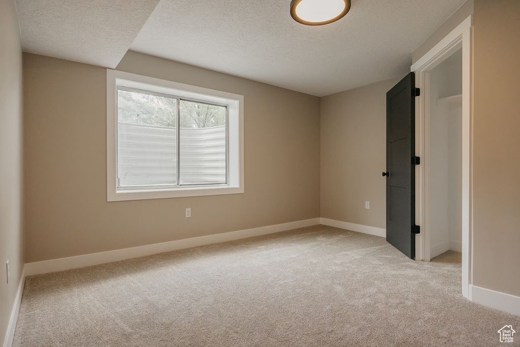 Spare room with a textured ceiling, light carpet, and baseboards
