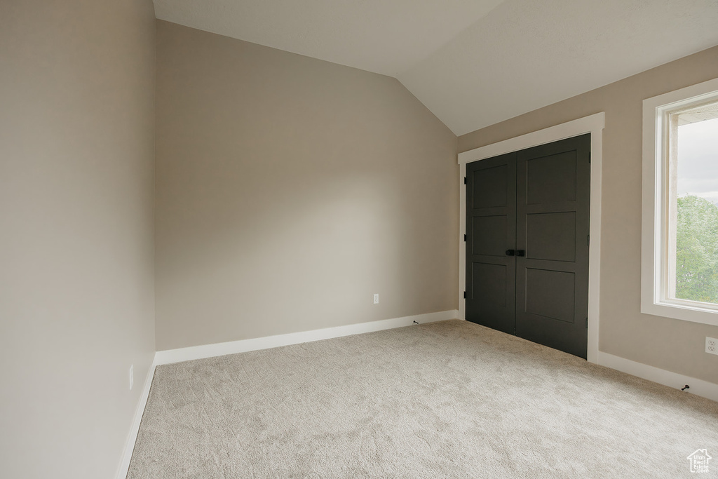 Unfurnished bedroom with carpet floors, baseboards, and lofted ceiling