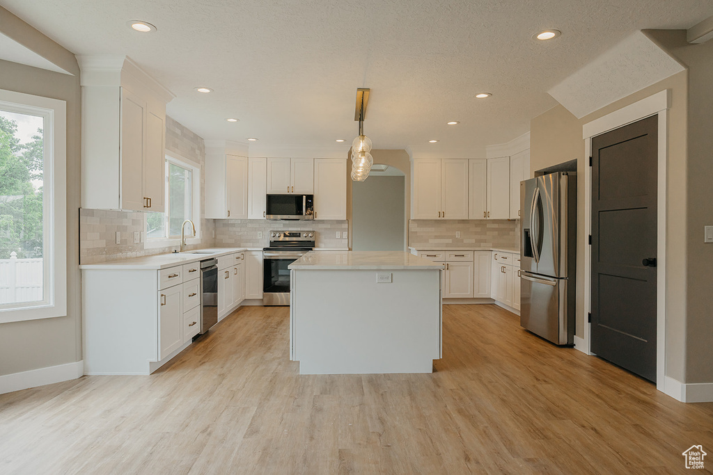 Kitchen featuring appliances with stainless steel finishes, light countertops, plenty of natural light, white cabinetry, and recessed lighting