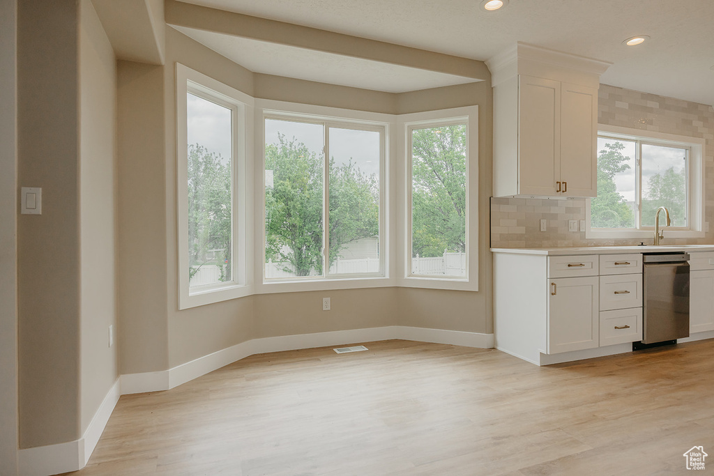 Kitchen featuring dishwasher, healthy amount of natural light, light countertops, baseboards, and recessed lighting
