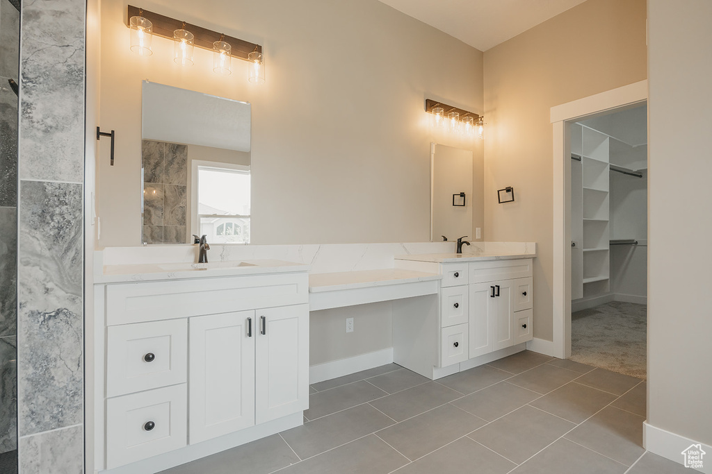Full bathroom featuring double vanity, tile patterned floors, baseboards, and a spacious closet
