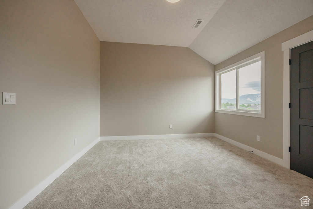Empty room with carpet, baseboards, and vaulted ceiling
