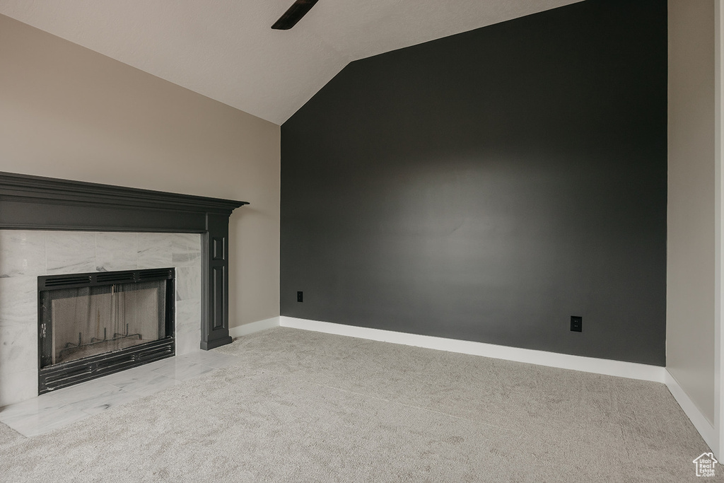Unfurnished living room featuring carpet, a ceiling fan, a tiled fireplace, baseboards, and high vaulted ceiling