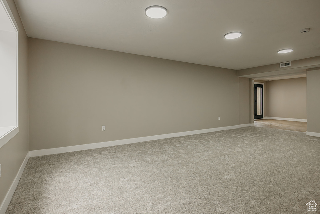 Empty room featuring light colored carpet, baseboards, and a smoke detector