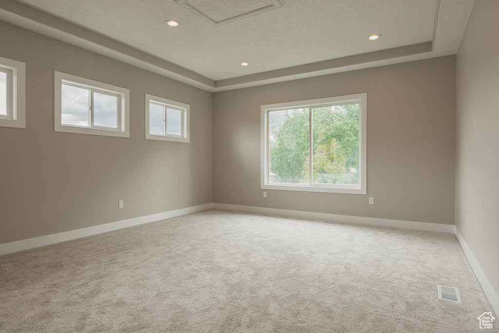 Carpeted empty room with a raised ceiling, baseboards, recessed lighting, and a textured ceiling