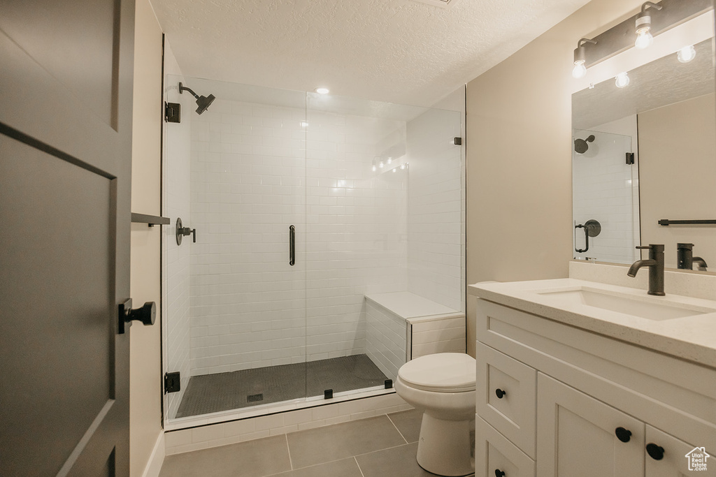 Full bath featuring tile patterned flooring, a shower stall, toilet, a textured ceiling, and vanity