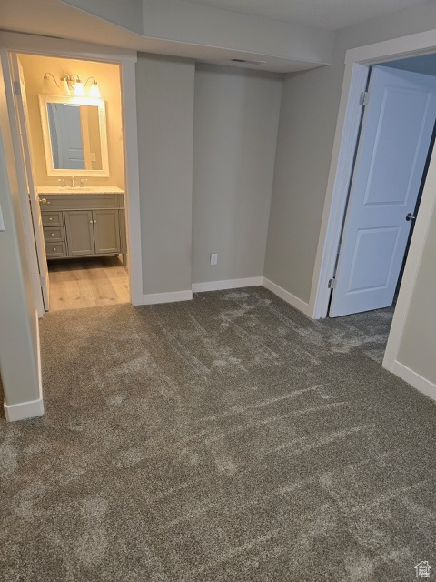 Unfurnished bedroom featuring carpet floors, baseboards, a sink, and ensuite bathroom