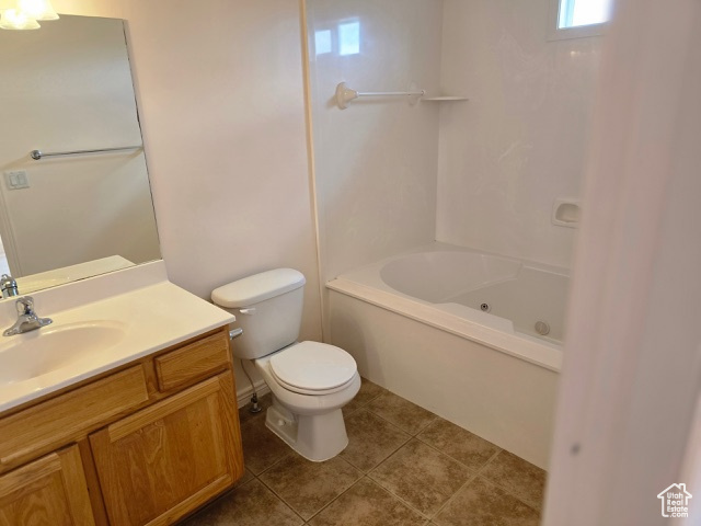 Bathroom with toilet, vanity, tile patterned flooring, and washtub / shower combination