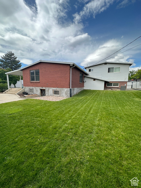 Back of house with a yard, brick siding, a carport, and concrete driveway