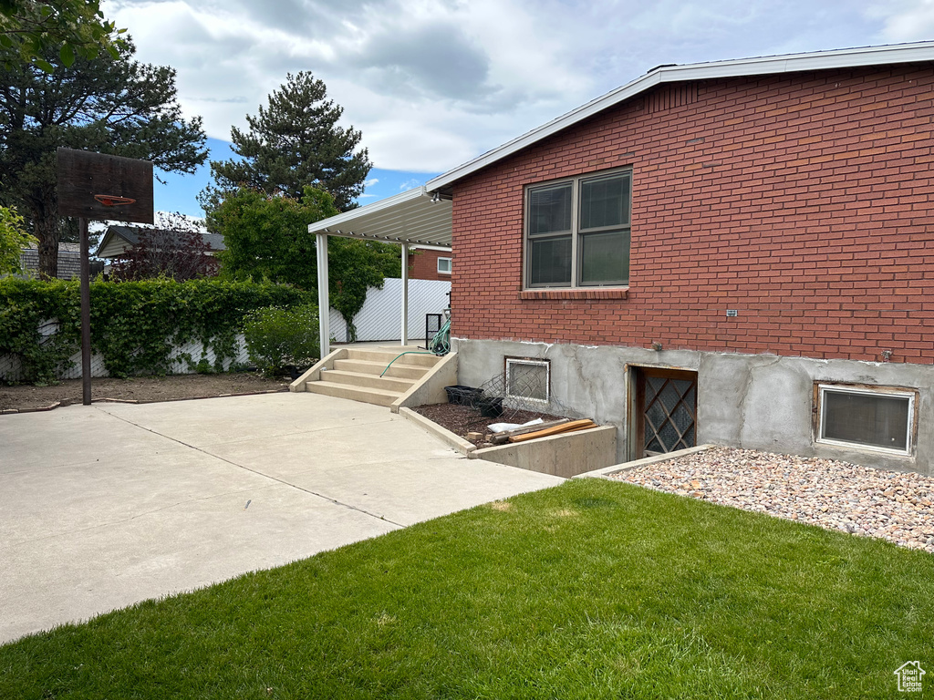 View of side of property featuring brick siding and a yard
