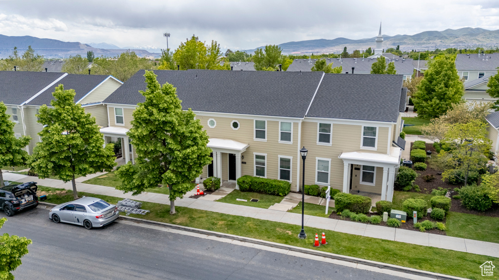 View of property with a mountain view, a front lawn, and a residential view
