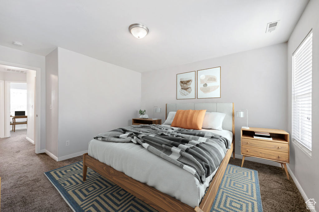 Carpeted bedroom featuring multiple windows and baseboards