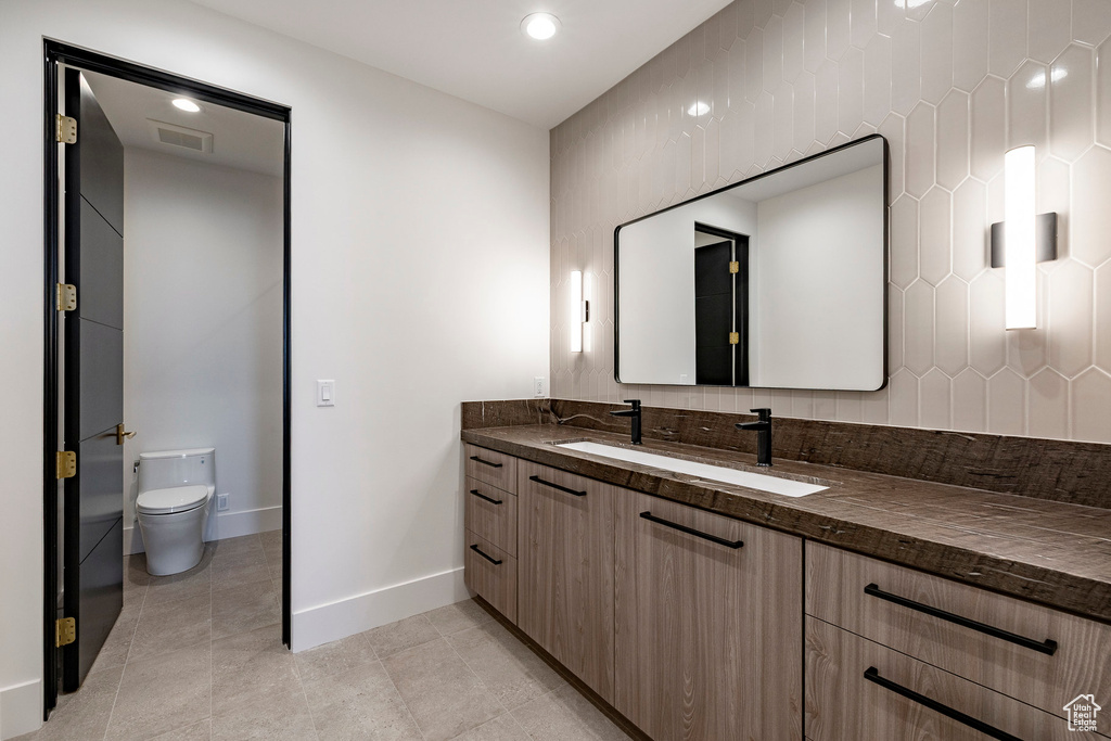 Bathroom with vanity, decorative backsplash, tile patterned floors, and recessed lighting