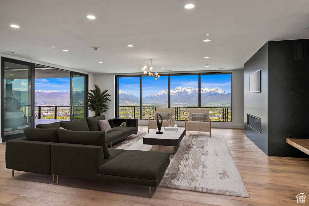 Living room featuring expansive windows, a mountain view, light wood finished floors, recessed lighting, and a fireplace