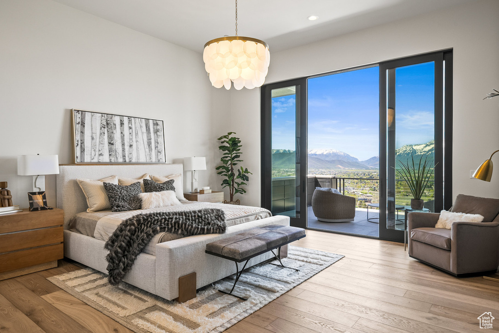 Bedroom featuring access to exterior, a mountain view, hardwood / wood-style flooring, recessed lighting, and a chandelier