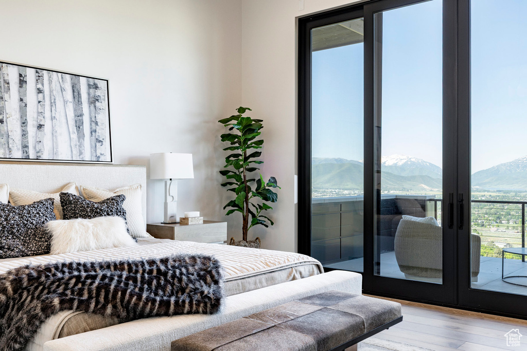 Bedroom with wood finished floors, access to outside, a mountain view, and french doors