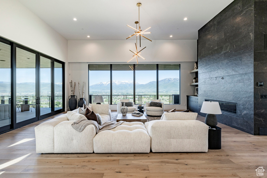 Living room with a mountain view, recessed lighting, a towering ceiling, a tile fireplace, and light wood-style flooring