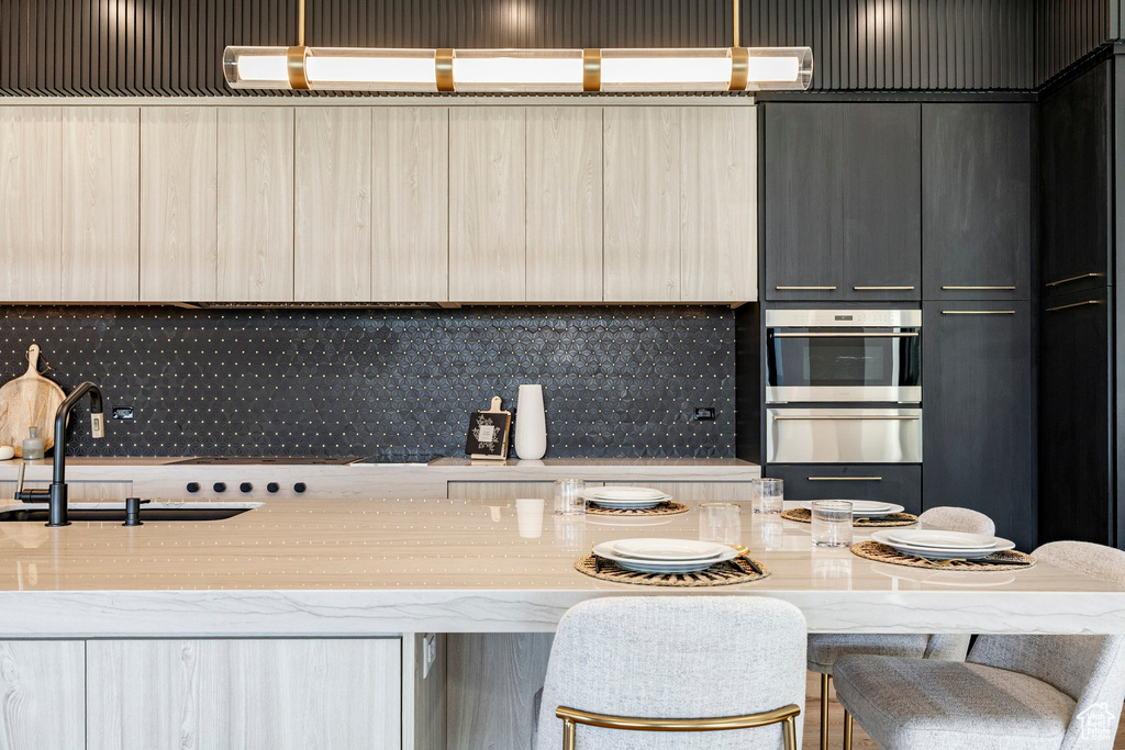 Kitchen with stainless steel oven, a warming drawer, backsplash, and modern cabinets