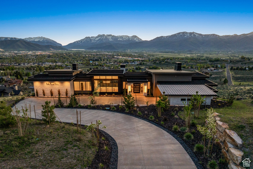 View of front of house featuring curved driveway, a mountain view, and a chimney