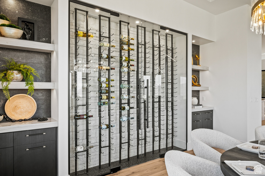 Wine area with wood finished floors and a chandelier