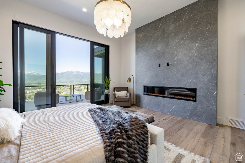 Bedroom featuring a tiled fireplace, wood finished floors, access to outside, recessed lighting, and a mountain view