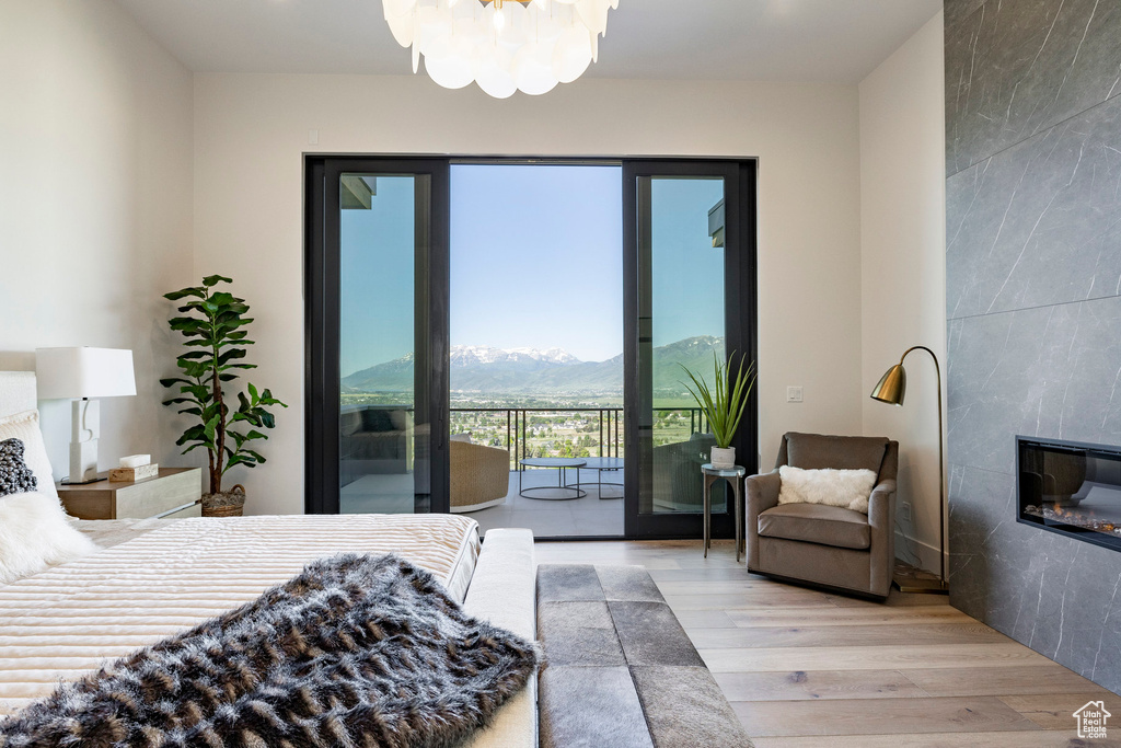 Bedroom featuring wood finished floors, access to exterior, a tile fireplace, a mountain view, and a chandelier