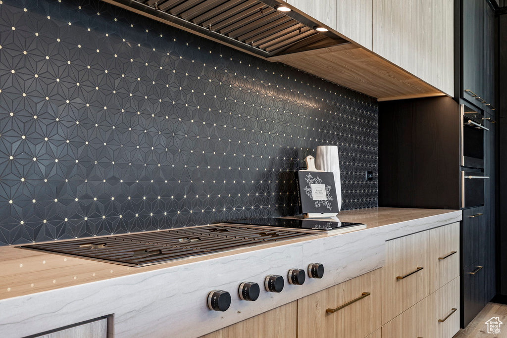 Kitchen featuring gas cooktop, light stone counters, tasteful backsplash, and modern cabinets