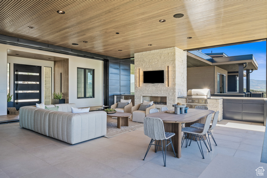 View of patio featuring grilling area, an outdoor kitchen, an outdoor living space with a fireplace, and outdoor dining area