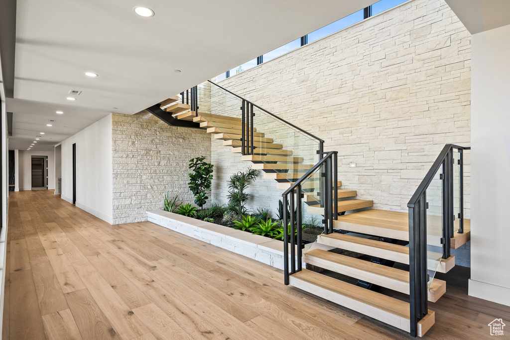 Stairway with hardwood / wood-style flooring, recessed lighting, baseboards, and a towering ceiling
