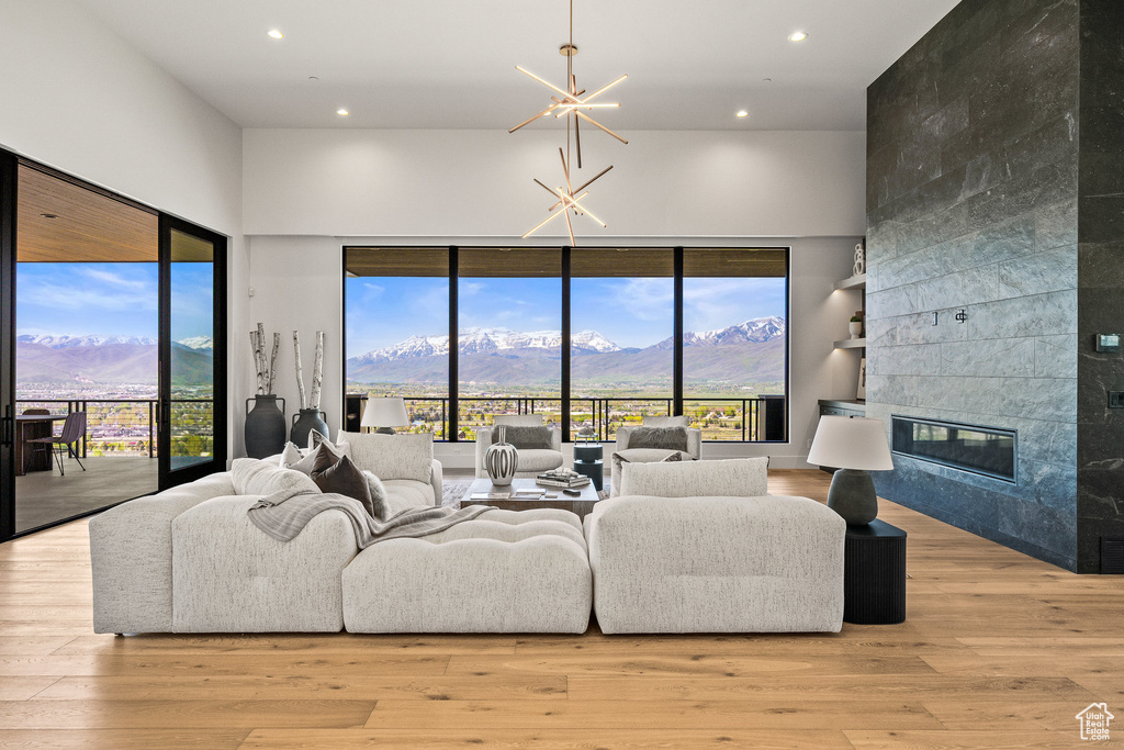 Living area with a high ceiling, recessed lighting, a mountain view, wood finished floors, and a fireplace