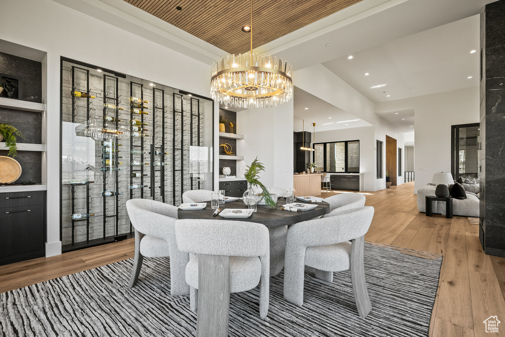 Dining space featuring a chandelier, hardwood / wood-style floors, recessed lighting, and a tray ceiling