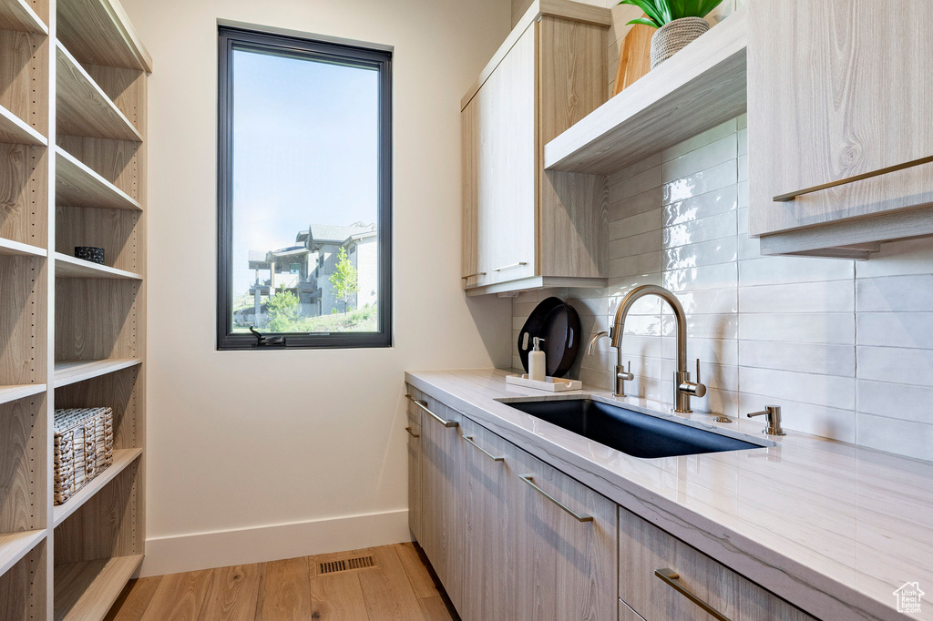 Kitchen with tasteful backsplash, light stone counters, healthy amount of natural light, and light wood-style flooring