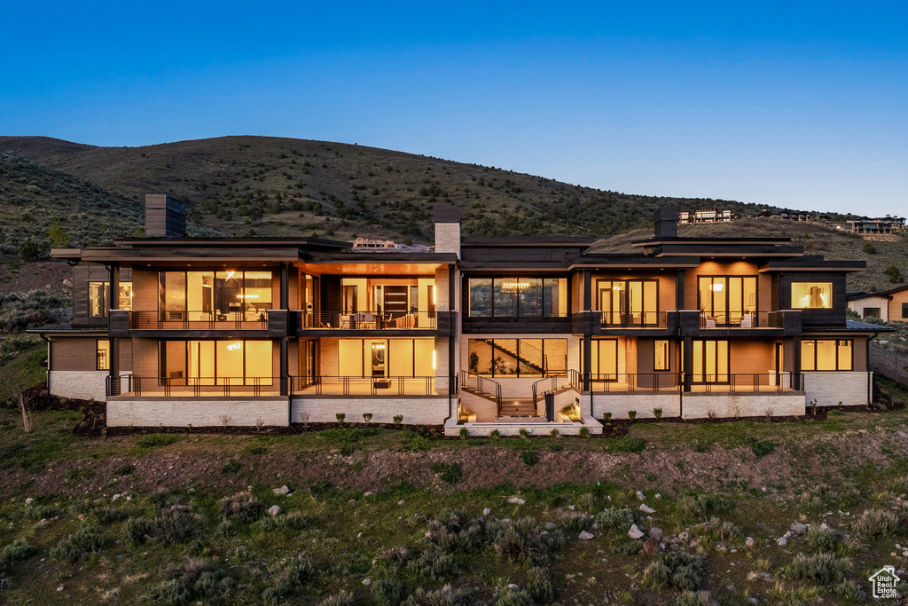Back of property featuring a chimney, a mountain view, and a balcony