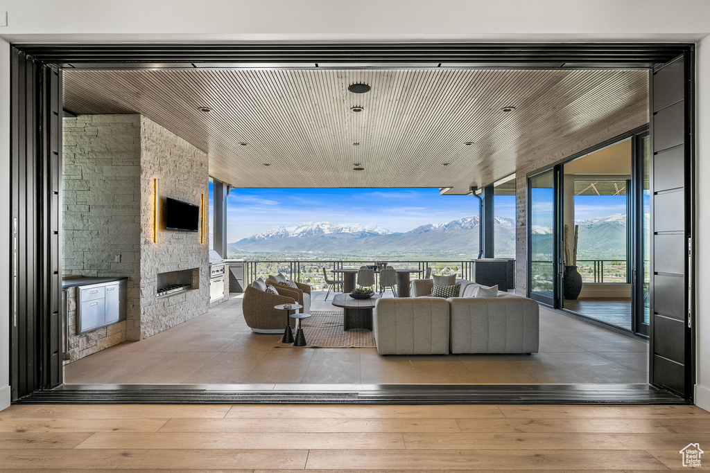 Living area featuring a wall of windows, an outdoor stone fireplace, hardwood / wood-style floors, and healthy amount of natural light