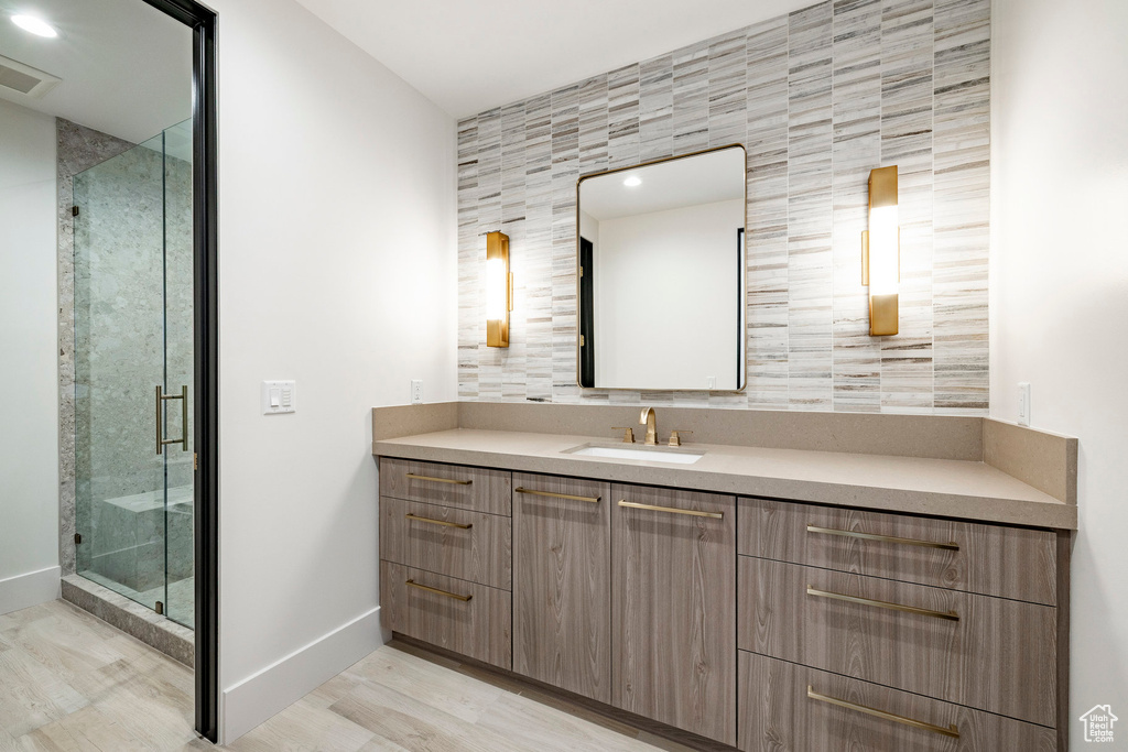 Full bathroom featuring vanity, a shower stall, wood finished floors, and tile walls