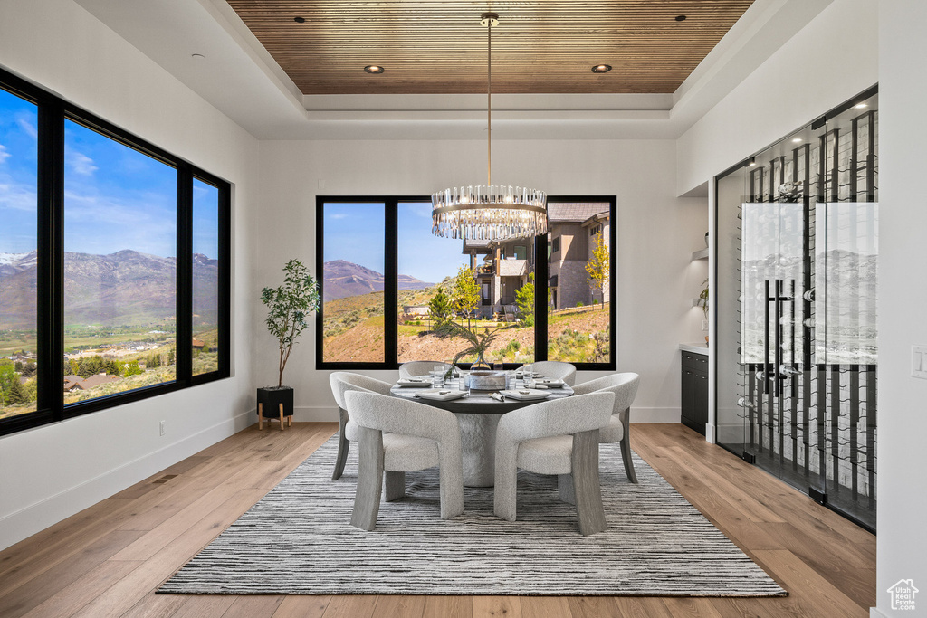 Dining room with a raised ceiling, wood ceiling, a chandelier, a mountain view, and hardwood / wood-style flooring