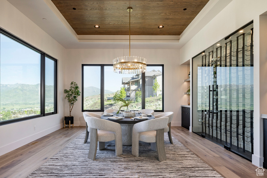 Dining space with wooden ceiling, a tray ceiling, a chandelier, light wood-style floors, and a mountain view