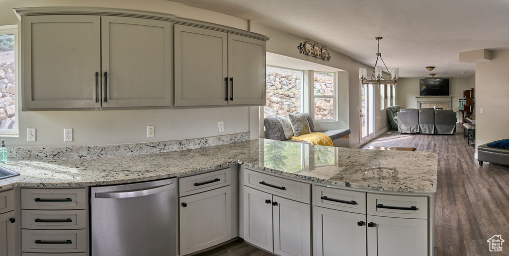 Kitchen featuring dishwasher, open floor plan, a peninsula, dark wood-style floors, and light stone counters