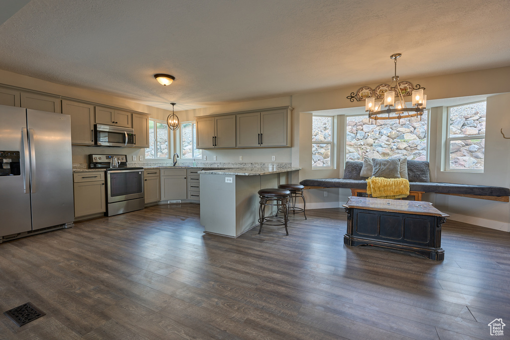 Kitchen featuring stainless steel appliances, a chandelier, gray cabinetry, a peninsula, and baseboards