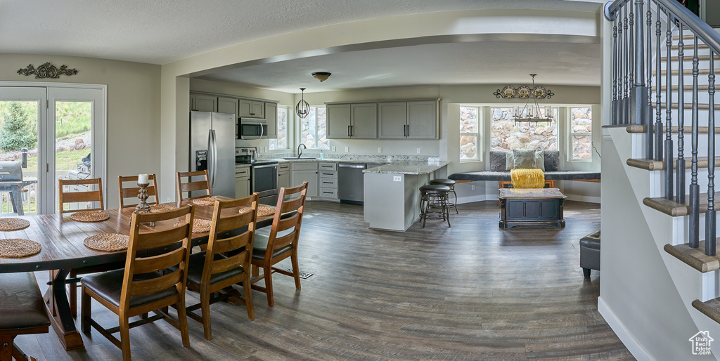 Dining area with stairway, dark wood finished floors, baseboards, and a chandelier