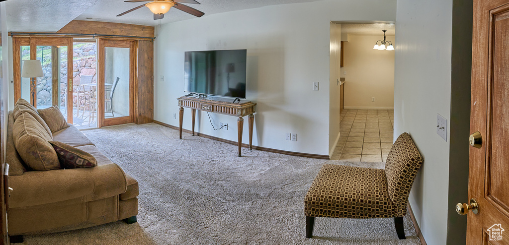 Carpeted living area with a ceiling fan, baseboards, and tile patterned floors