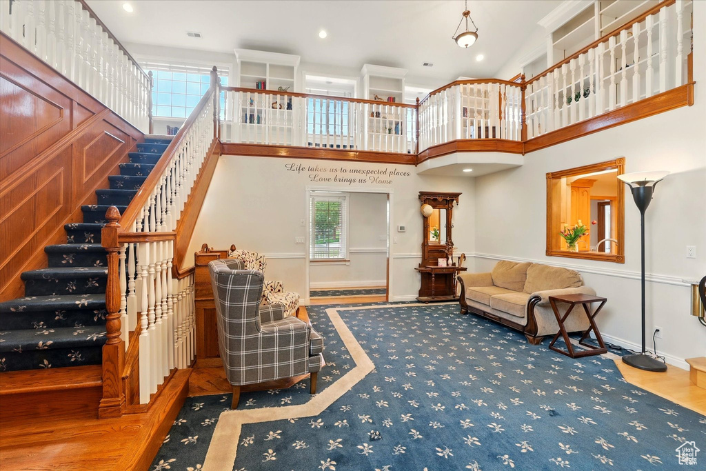 Living room with stairway, baseboards, wood finished floors, recessed lighting, and a high ceiling