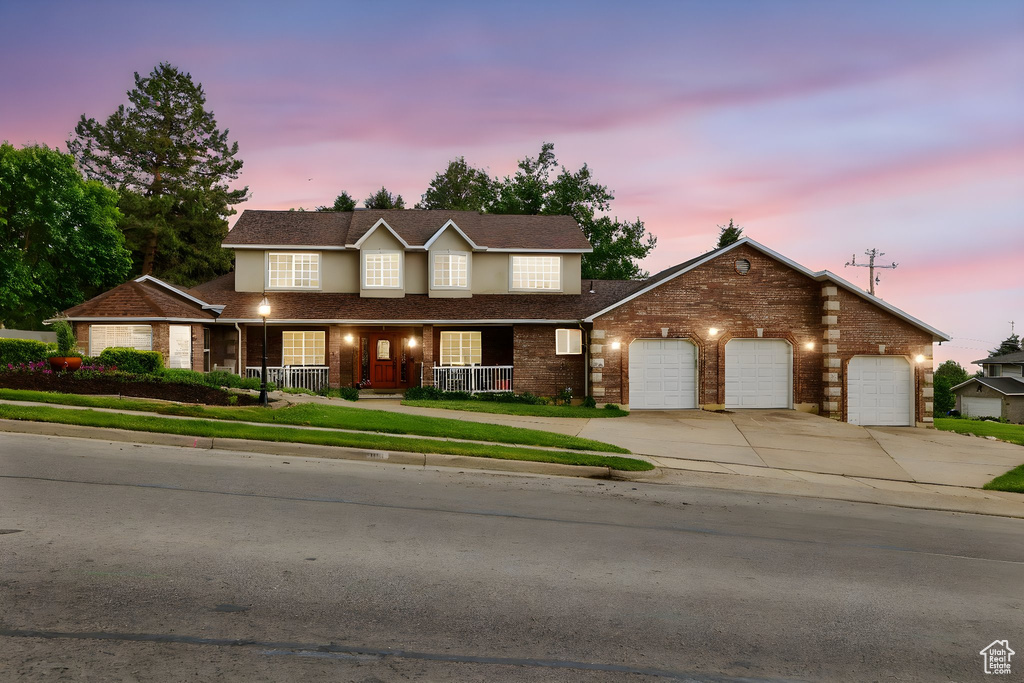 View of front facade featuring a porch, concrete driveway, an attached garage, and brick siding