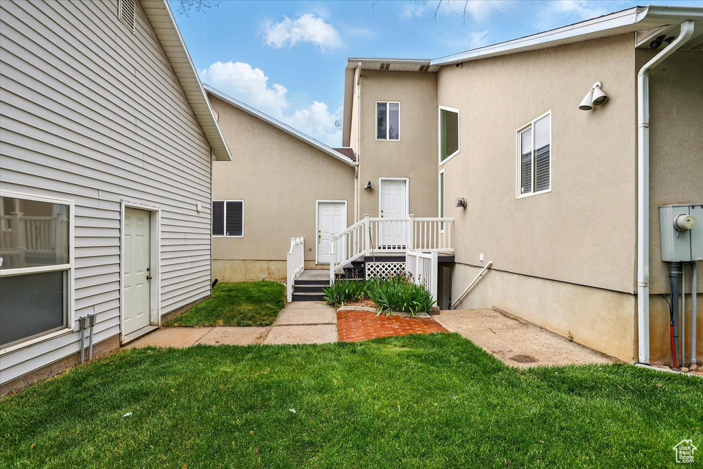 Rear view of property featuring a lawn and stucco siding