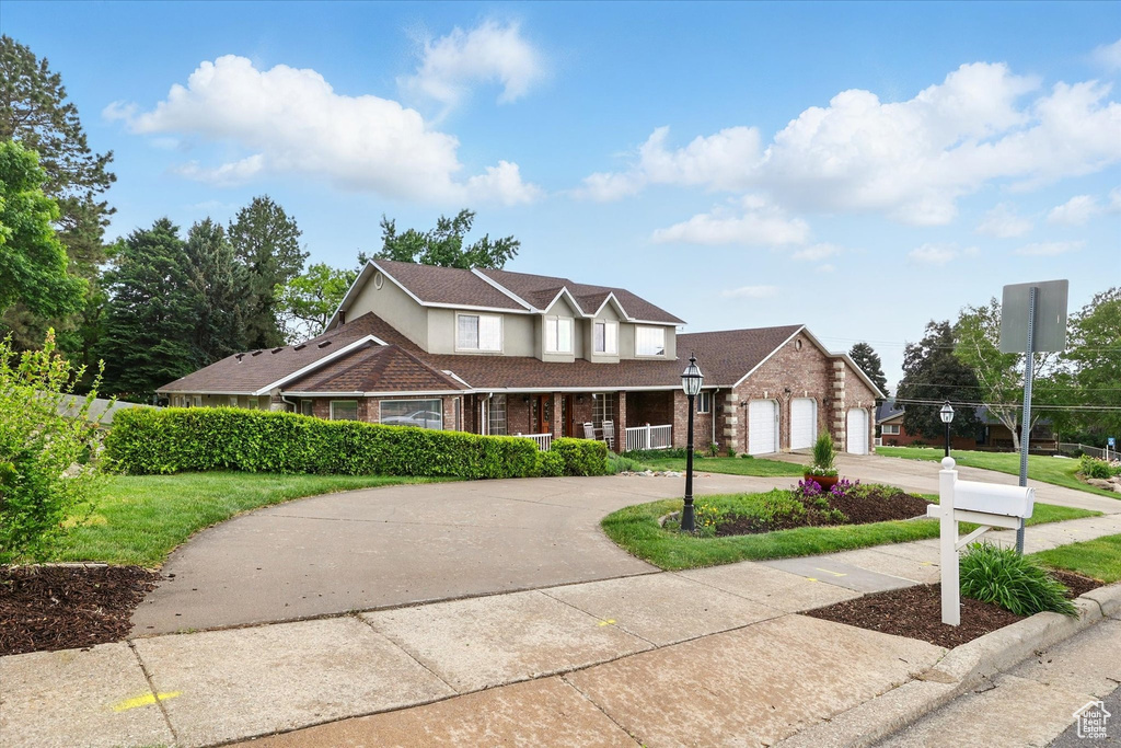 Traditional-style house featuring curved driveway, a porch, brick siding, and a garage